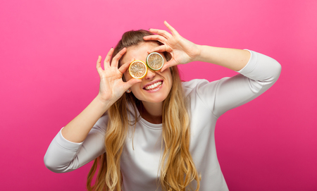 Funny woman looking through orange slice and smilingの写真素材