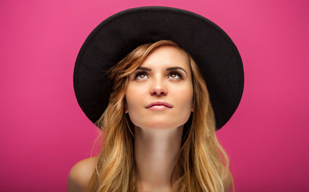 Beautiful young woman with hat and long blonde hair over pink backgroundの写真素材