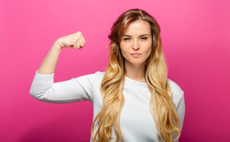 Successful woman raising hand in success gesture over pink backgroundの写真素材