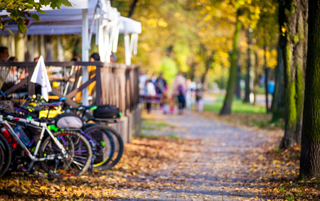 Blurred background, autumn park alley with bicycles and peopleの写真素材