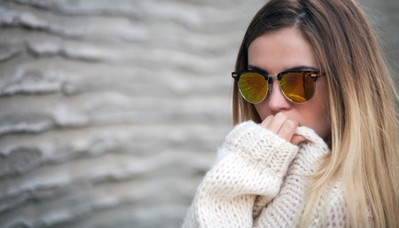 Young girl with sunglasses posing in front of concrete wallの写真素材