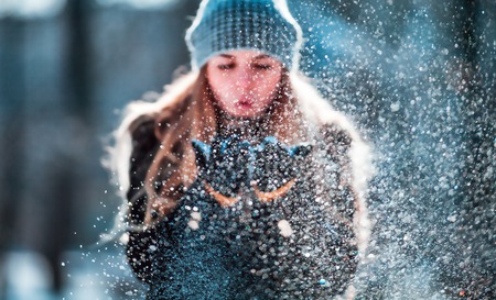 Beautiful winter woman blowing snow outdoor, flying snowflakesの写真素材