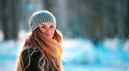 Happy young woman walking in winter park at sunny dayの写真素材