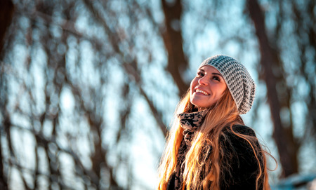 Portrait of smiling beautiful woman in the winter park at sunny dayの写真素材
