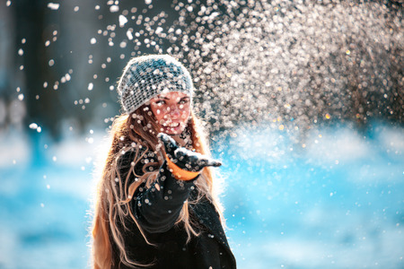 Smiling woman throwing snow in the air looking at cameraの写真素材