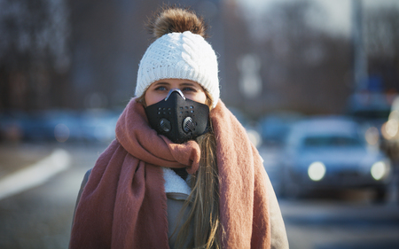 Young woman wearing protective mask in the city street, smog and air pollution during winterの写真素材