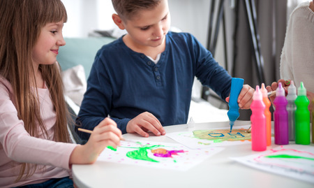 Loving family, mother with children together paint at home