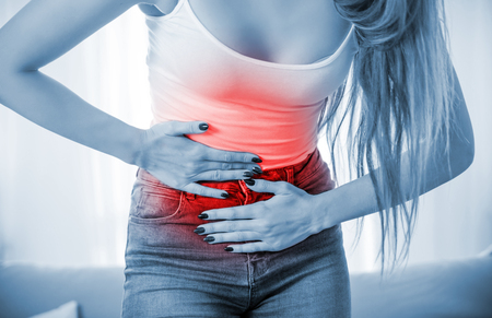 Young female at home suffering from abdominal pain, close upの写真素材