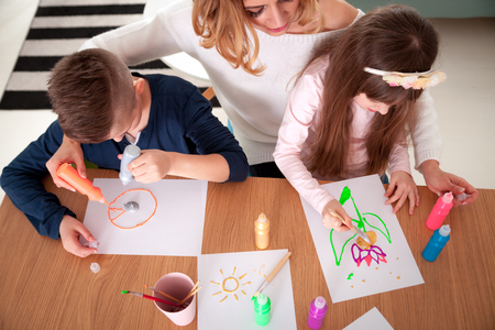 Happy loving family mother with children together paint at homeの写真素材