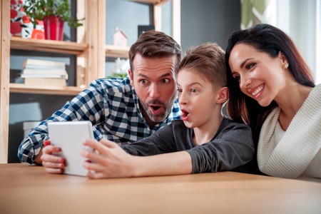 Happy family using digital tablet taking selfie at home