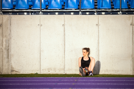 Fitness woman resting after training on stadium running trackの写真素材