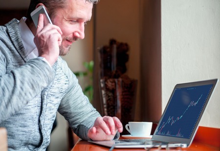 Investor analyzing stock market with charts on laptop screen at restaurant
