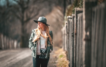 Woman with vintage camera and hat walking on rural countryの写真素材