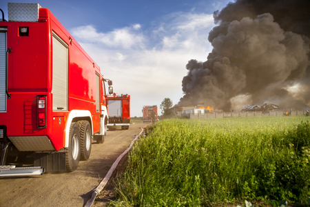 Red fire truck in action with landfill fire in backgroundの写真素材