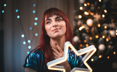 Cheerful woman holding Christmas light decoration in living room
