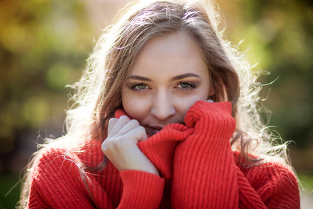 Natural young woman in soft warm knitted sweater walking outdoors, autumn and springの写真素材