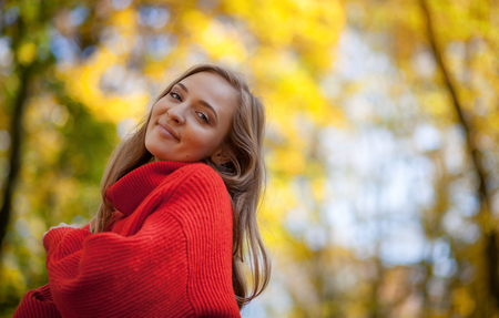 Beautiful smiling young woman in soft knitted sweater walking outdoor, positive feelingsの写真素材