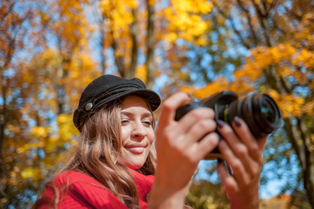 Young woman having fun with camera making photos at green parkの写真素材