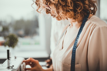 Tailor during work using sewing machine, fashion designer at workshopの写真素材