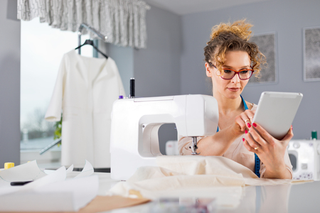 Tailor during work using digital tablet, modern fashion designer at workshopの写真素材