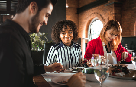 Young black businesswoman smiling during business lunch in restaurant, corporate meeting conceptの写真素材