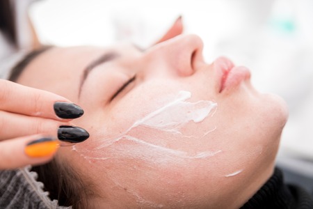 Beautician applying facial mask at cosmetic clinic, cosmetology treatment skincare face