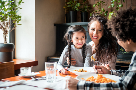 Happy african american family eating lunch together at restaurant and having funの写真素材