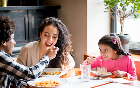 Happy african american family eating lunch together at restaurant and having funの写真素材