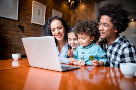 Happy multiethnic family having fun while using laptop togetherの写真素材