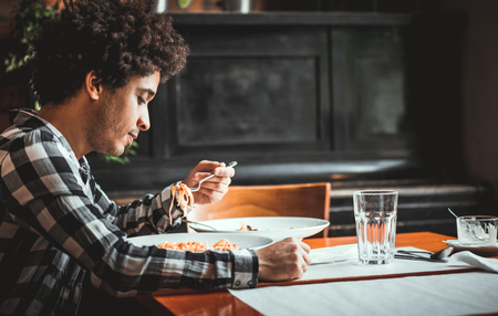 Young african american man eating lunch at restaurantの写真素材