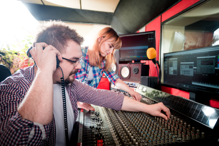 Music engineer and musician working together in recording studio using mixing deskの写真素材