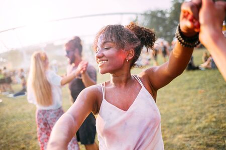 African American young woman with friends dancing at summer holi festivalの写真素材