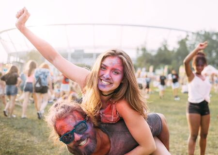 Beautiful couple covered in colorful powder having fun at summer holi festival