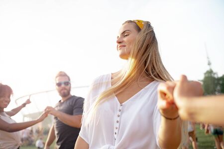Beautiful young blonde woman dancing with friends outdoor at music festivalの写真素材