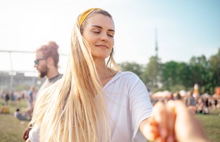 Beautiful young blonde woman dancing with friends outdoor at music festivalの写真素材