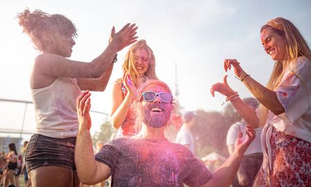Multiethnic group of friends throwing colorful powder at holi festivalの写真素材