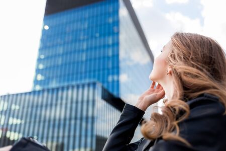 Beautiful smiling woman looking at modern office buildings in modern cityの写真素材