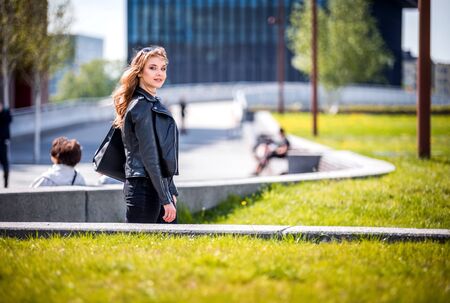 Young woman walking on modern green city areaの写真素材