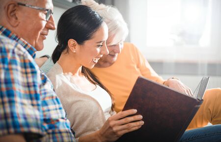 Senior couple with their daughter looking at photos in family album together