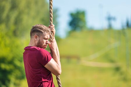 Overcome obstacle using rope during extreme race in the boot camp
