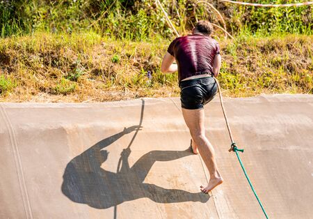 Fit man using rope during obstacle course training in the boot camp