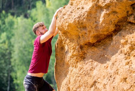 Fit man climbing on rocks obstacles in the boot campの写真素材
