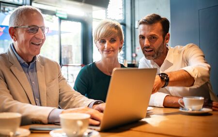 Business people looking at laptop at cafe and discussingの写真素材