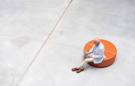 Senior businessman using laptop sitting alone top view, copy space backgroundの写真素材