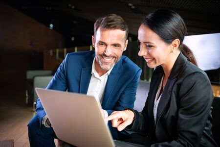 Businesswoman with laptop talking with colleague during meetingの写真素材