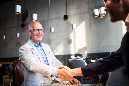 Senior businessman shaking hands during meeting in cafeの写真素材