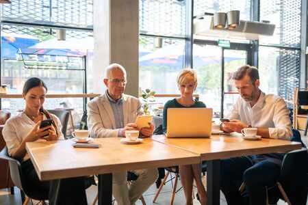 Group of business people using electronic devices in cafeの写真素材