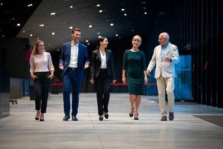 Diverse group of business people of all ages walking together and talking in modern interiorの写真素材