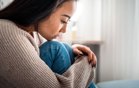 Sad lonely depressed asian woman on sofa at homeの写真素材