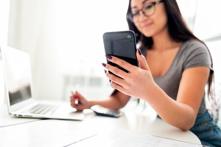Asian woman using smartphone app and laptop for calaulating home budget finance taxesの写真素材